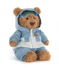 Stuffed teddy bear wearing a blue snowsuit with a hood on a white background