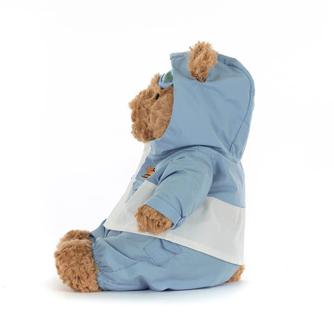 Side view of a Stuffed teddy bear wearing a blue snow suit on a white background