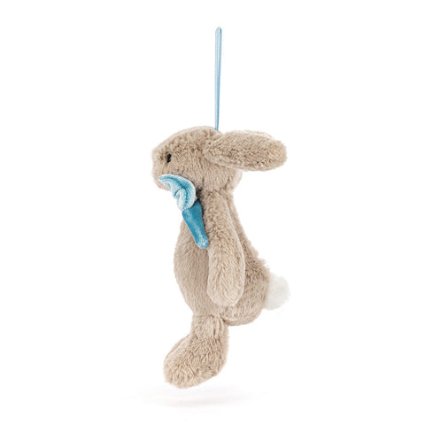 side view of a Plush bunny toy with blue bow tie on a white background. It hangs from a blue ribbon.
