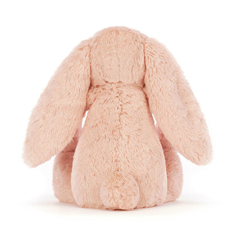 Pink plush bunny toy on a white background from behind