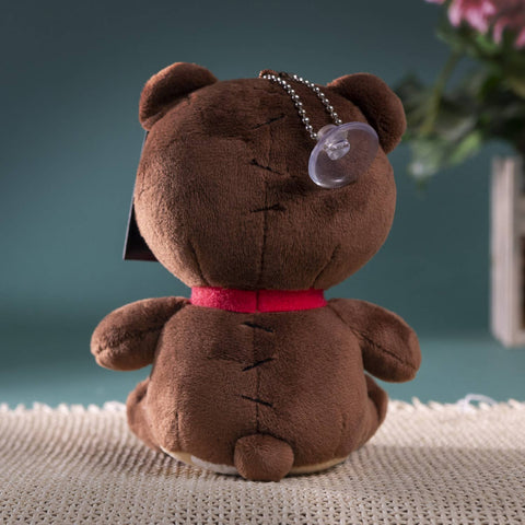 Image shows a back view of the teddy bear. It has a suction cup hanging from a chain attached to its head.
