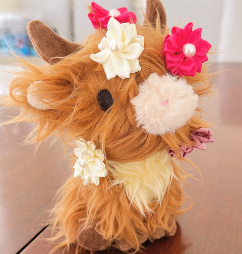 Plush highland cow with floral clips attached to his head and neck