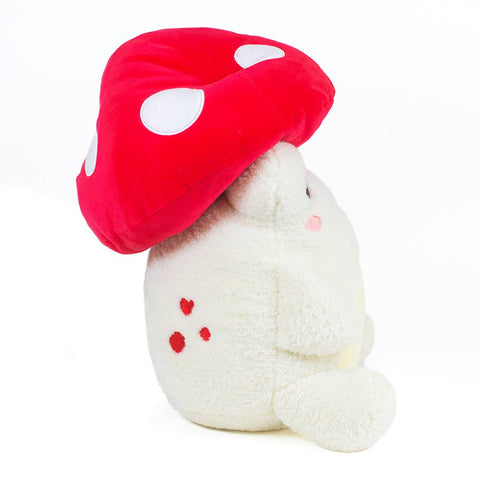 Image shows a side view of the stuffed frog wearing a mushroom hat
