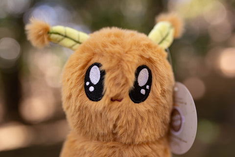 Image shows a closeup of the stuffed moth's face. It is a tan color.