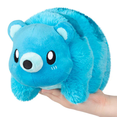 Blue plush tardigrade toy held in a hand on a white background