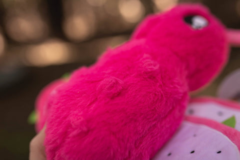 Image shows a closeup of the fur of the stuffed moth. It is faux dark pink fur.