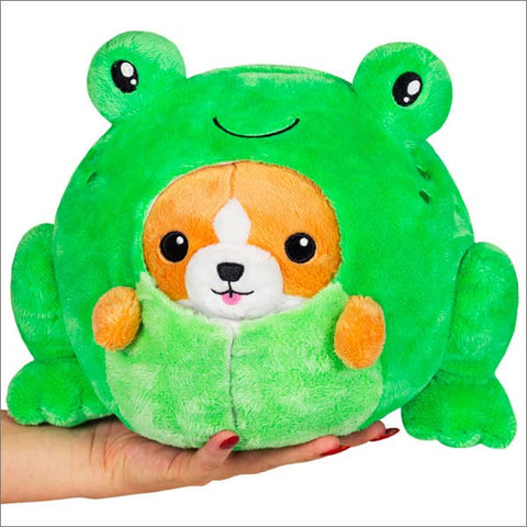 Plush toy shaped like a Corgi in a frog costume held by a hand on a white background