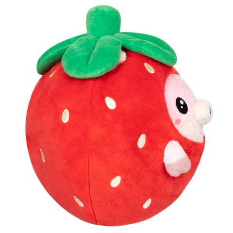 A side view of the plush pig wearing a strawberry costume