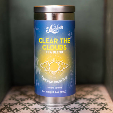 Tea blend canister labeled 'Clear the Clouds' on a patterned surface with a dark background