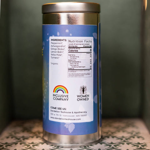 Tin tea container with a blue label on a patterned surface. Label lists ingredients and nutrition facts.