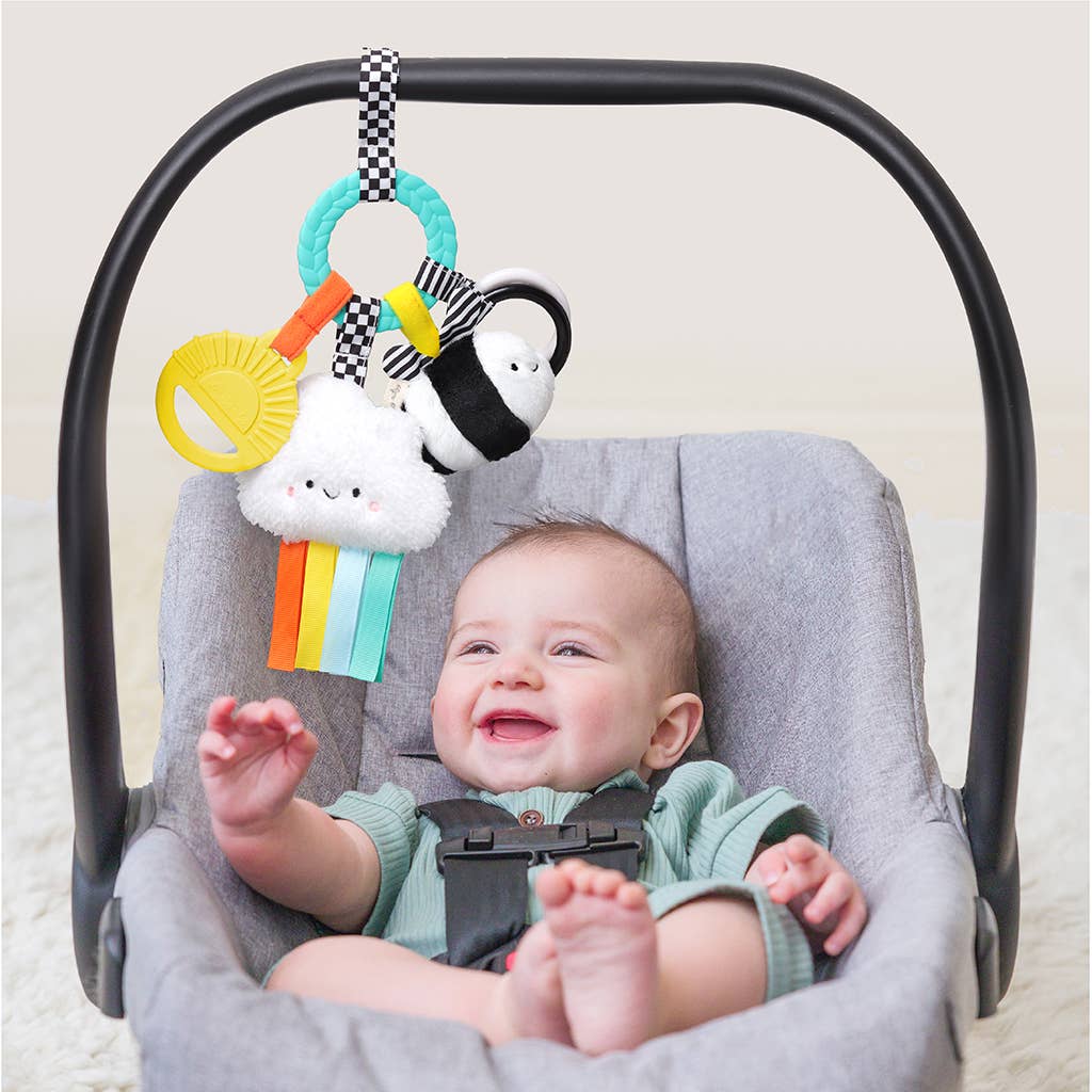 Image shows the toy attached to a baby's car seat. Baby plays happily with the toy.