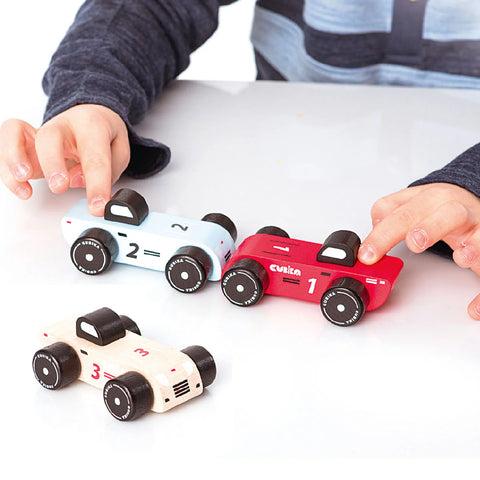 Image shows a young child playing with the wooden toy cars