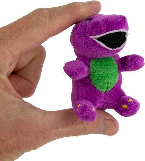 Image shows the world's smallest Barney plush held between an adult's thumb and forefinger.