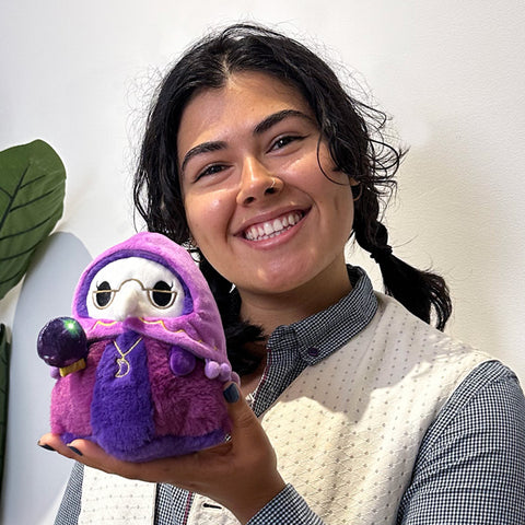 A woman holds the fortune teller plague doctor. It is slightly smaller than her head.