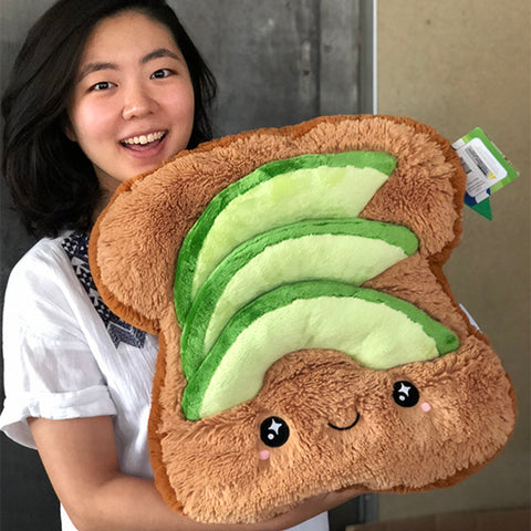 A woman holds the plush avocado toast. It is about the size of her torso.