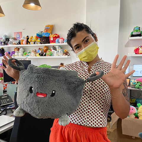 A woman wearing a mask holds the plush cauldron. It is about the size of her torso.