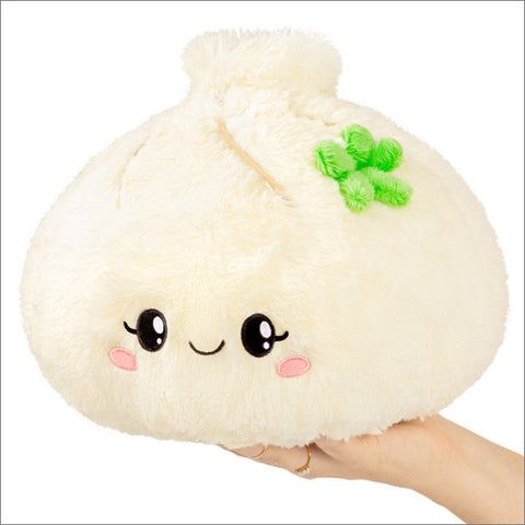 A person holds a plush soup dumpling with a smiley face on a white background
