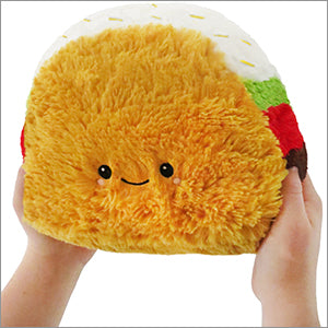 A plush toy designed to look like a mini taco with a smiling face, made of soft orange fabric.