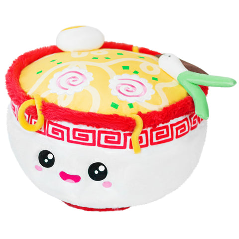 A plush toy resembling a bowl of ramen with cute facial features, colorful toppings, and an egg.