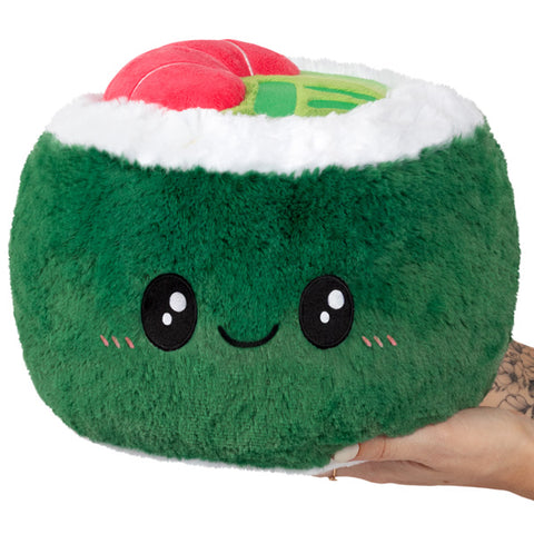 A plush green sushi roll with a happy face, held in someone's hand