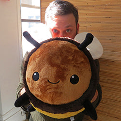 A man holds up the plush bumblebee. It is about the size of his torso.