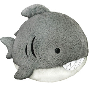 A gray plush toy in the shape of a Great White Shark with a wide smile showing white teeth.