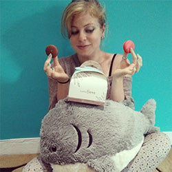 A woman sits with the plush Great White Shark in front of her. It is approximately the size of her torso.