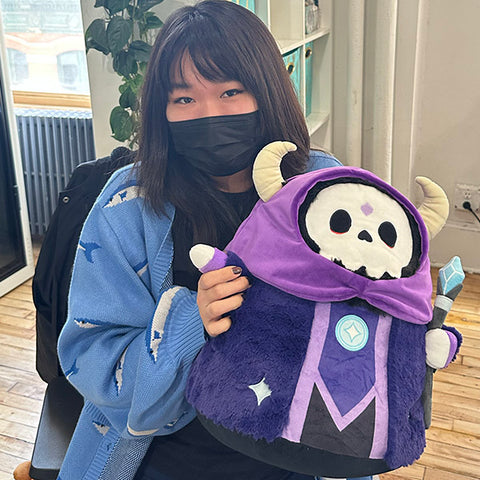 A woman holds the plush Lich. It is about the size of her torso.