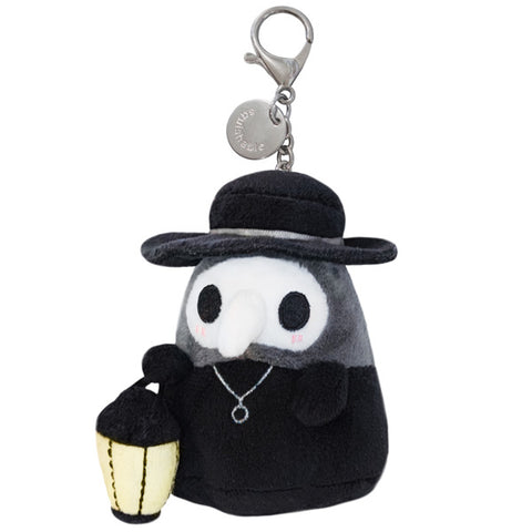 A plush toy resembling a micro plague doctor with a black coat, white mask, and a small lantern, complete with a metal clip.