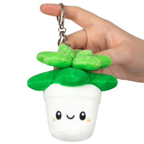 A plush succulent plant in a white pot with a smiley face, attached to a silver clip keychain