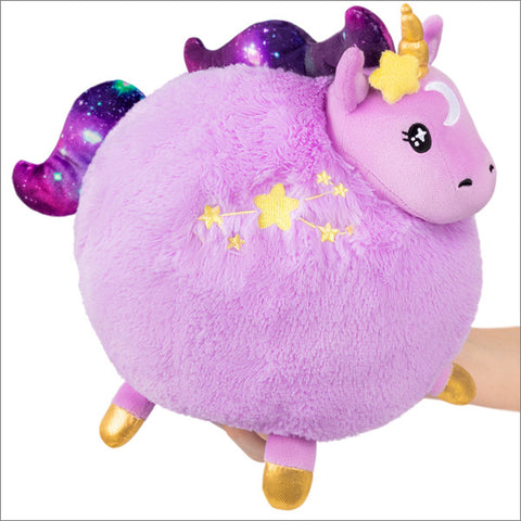 A lavender plush unicorn with a round body, starry mane and tail, and gold hooves held in someone's hand
