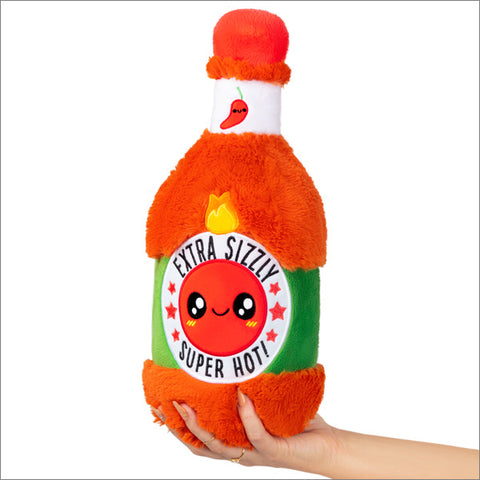 A plush bottle of hot sauce with a happy face held in someone's hand