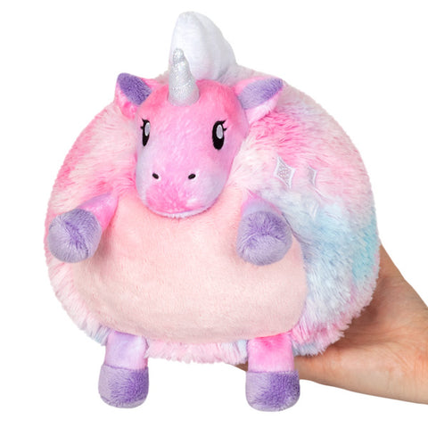 A plush pastel tie-dye unicorn with a round body held in someone's hand