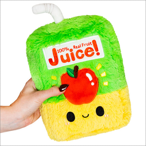 A hand holding a green and yellow plush toy designed to look like a mini juice box with a stylized apple graphic.