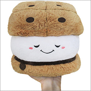 A plush s'more with a happy face, held in a hand on a white background
