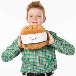 A young boy holds the stuffed s'more. It is larger than his head.