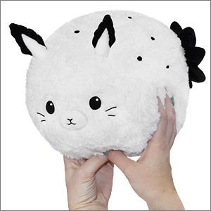 A plush sea bunny stuffed animal being held in someone's hands. It is white with black spots and has a round, soft body.