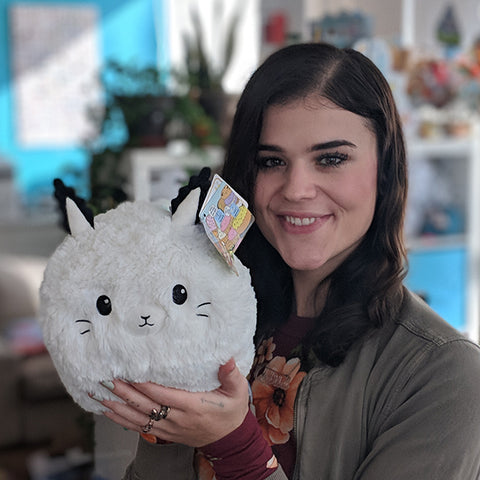 A woman holds the plush sea bunny near her face. It is slightly larger than her head.