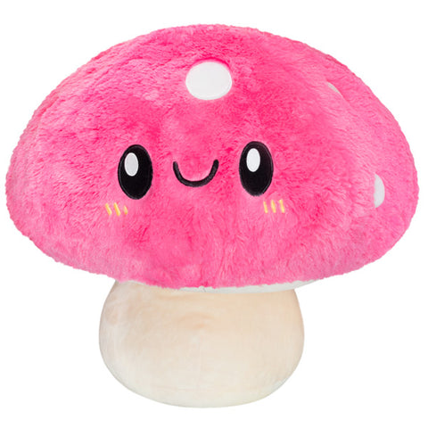 A plush pink mushroom toy with a happy face on a white background
