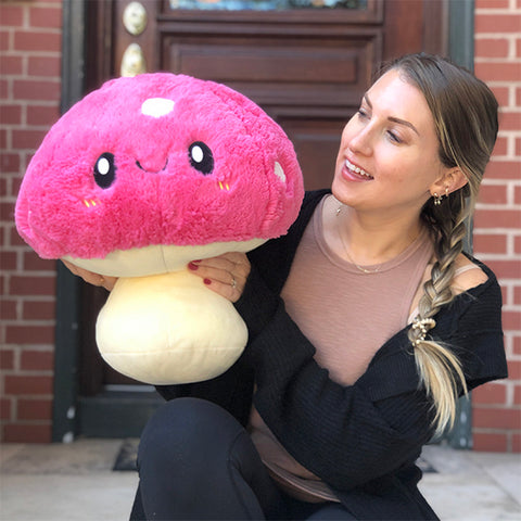 A woman holds the plush mushroom. It is about the size of her torso.