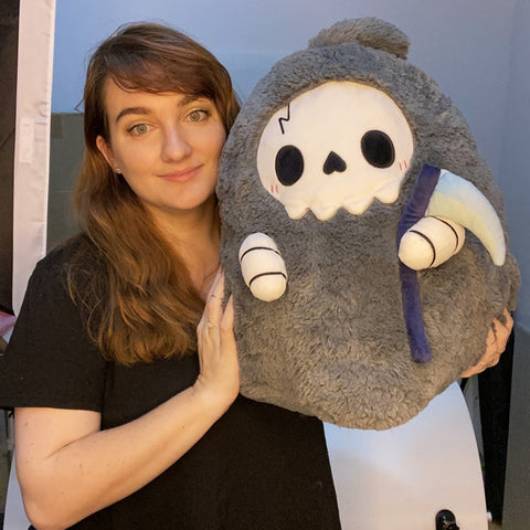 A woman holds the plush Reaper. It is about the size of her torso.
