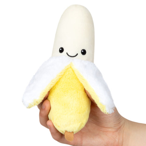 A plush toy resembling a banana with a smiling face, held in a person's hand.