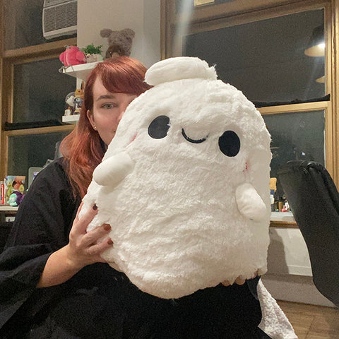 A woman holds the plush ghost. It is about the size of her torso.