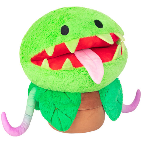 A plush toy resembling a Venus Fly Trap with a green body, red mouth with teeth, and black eyes.