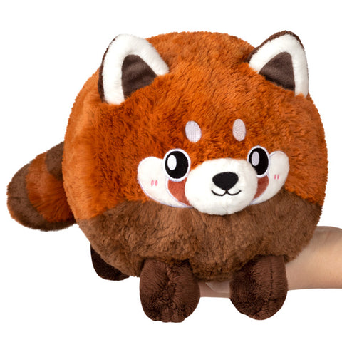 A plush red panda with a round body held in someone's hand